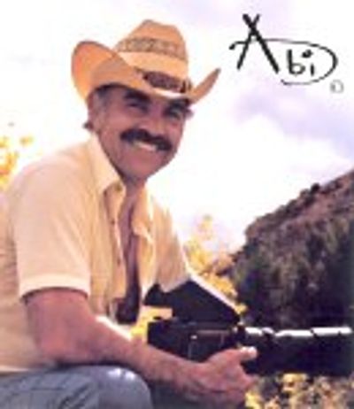 a man in a straw cowboy hat with a mustache holds a camera with a telephoto lens