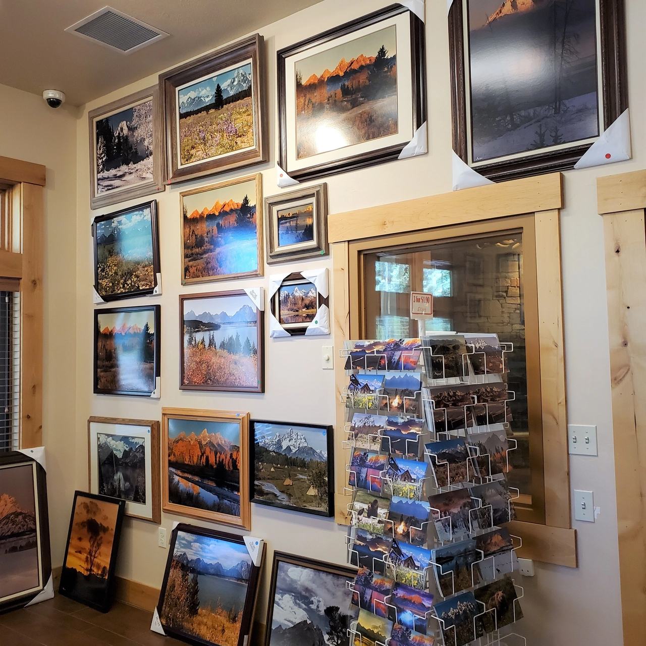 a wall full of scenic mountain paintings for sale